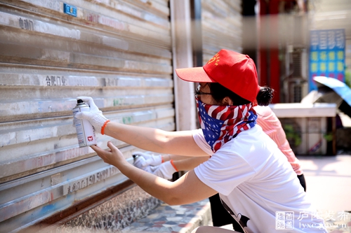 志愿者清理用喷漆覆盖路边卷闸门上的油漆小广告.JPG